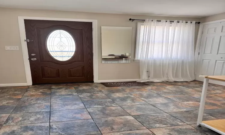 Entryway with stone finish flooring and baseboards