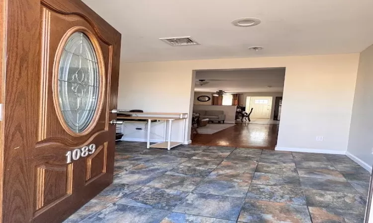 Foyer featuring stone finish flooring, visible vents, ceiling fan, and baseboards