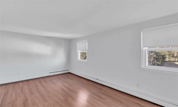 Unfurnished room with a baseboard radiator and wood finished floors