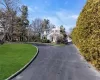 View of front of house featuring aphalt driveway, a chimney, and a front lawn