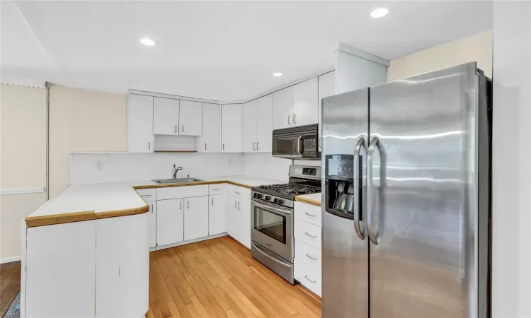 Kitchen featuring light wood flooring, appliances with stainless steel finishes, a peninsula,