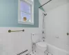 Full bathroom with shower / bathtub combination, a baseboard radiator, a wainscoted wall, and tile walls