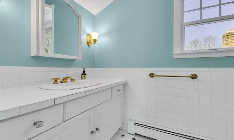 Bathroom with a baseboard heating unit, a wainscoted wall, tile walls, and vanity