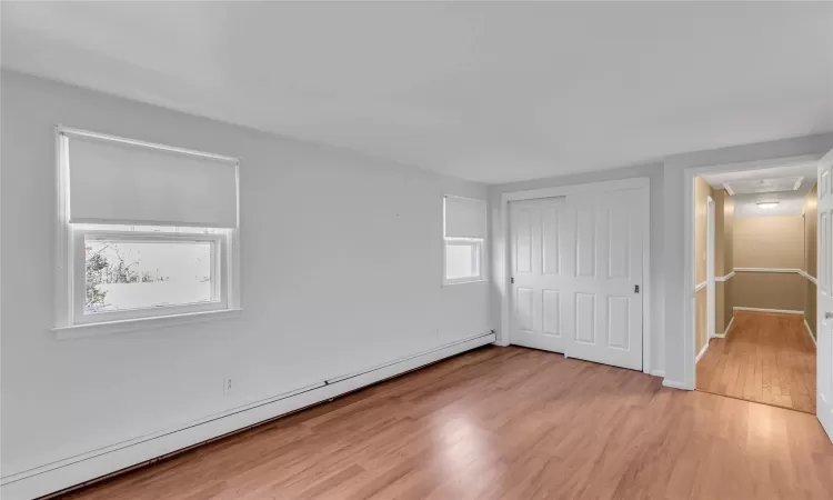 Unfurnished room featuring light wood finished floors, baseboards, and a baseboard heating unit