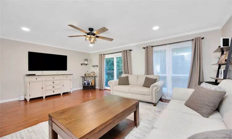 Living room with ceiling fan, crown molding, baseboards, and wood finished floors