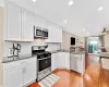 Kitchen featuring white cabinets, open floor plan, a peninsula, stainless steel appliances, and a sink