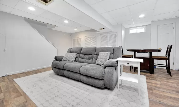 Living area featuring a paneled ceiling, wood finished floors, and visible vents