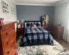 Bedroom featuring visible vents, ornamental molding, and wood finished floors