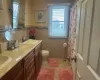 Bathroom with tile walls, double vanity, toilet, a sink, and tile patterned flooring