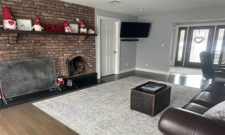 Living area with visible vents, a fireplace, baseboards, and wood finished floors