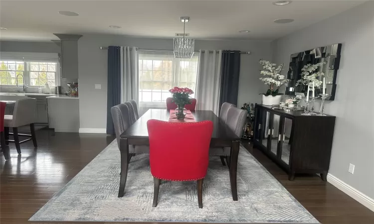 Dining room with a notable chandelier, visible vents, baseboards, and dark wood-style flooring