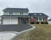 Traditional-style home with aphalt driveway, brick siding, an attached garage, and a front lawn