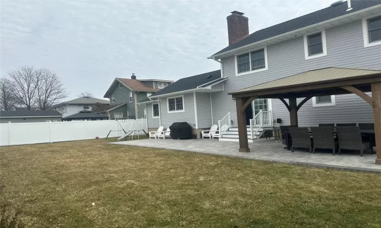 Back of property featuring a patio, fence, a yard, a gazebo, and a chimney