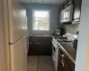 Kitchen featuring white appliances, a sink, backsplash, tile patterned floors, and dark stone countertops