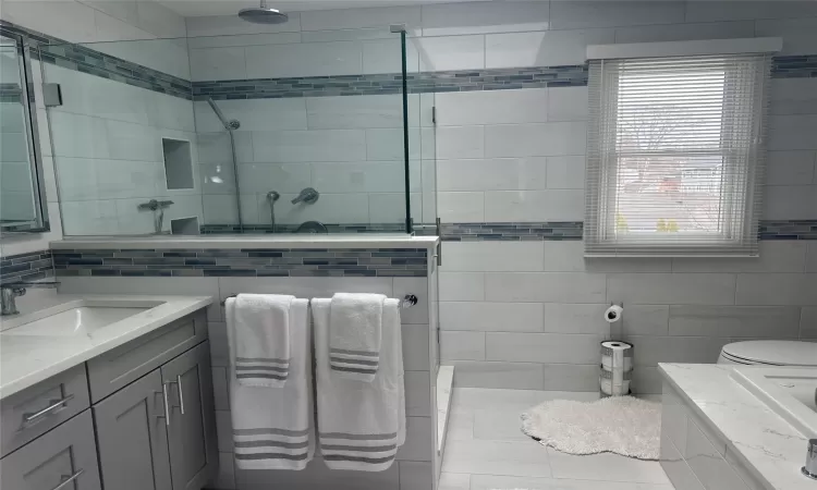 Full bathroom featuring tile walls, a shower stall, and vanity