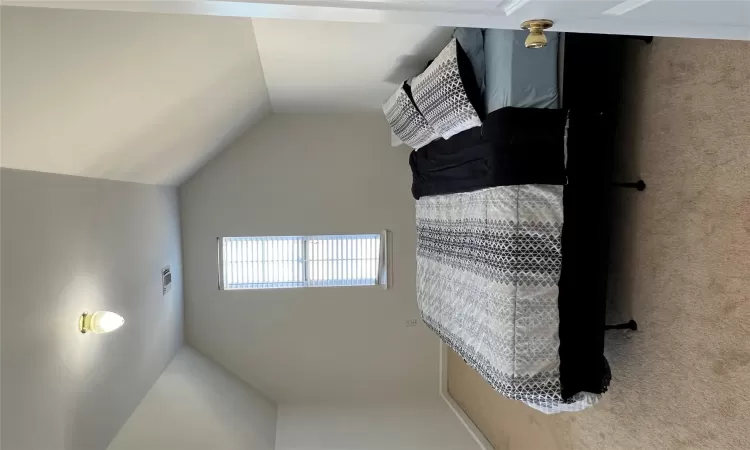 Carpeted bedroom with vaulted ceiling and visible vents