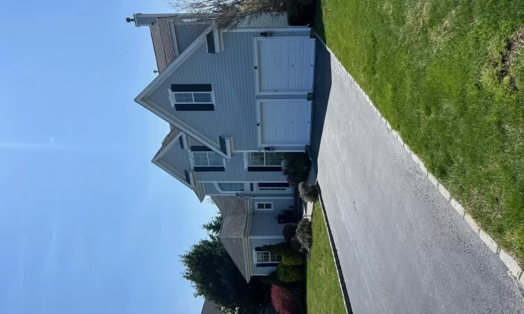 View of front of property featuring a front yard, driveway, a chimney, and an attached garage