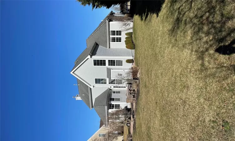 Rear view of house featuring a chimney and a lawn