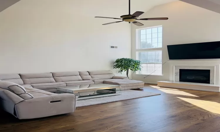 Living room featuring high vaulted ceiling, dark wood-style flooring, ceiling fan, and a premium fireplace