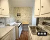 Kitchen featuring light countertops, gas range gas stove, a sink, and white cabinetry