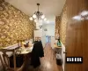 Dining area featuring a notable chandelier, wainscoting, wood finished floors, and wallpapered walls