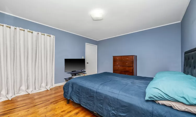 Bedroom featuring crown molding, baseboards, and wood finished floors