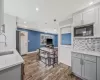 Kitchen featuring tasteful backsplash, dark wood-type flooring, gray cabinetry, black microwave, and a sink