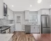 Kitchen featuring light stone counters, dark wood finished floors, stainless steel appliances, visible vents, and a sink