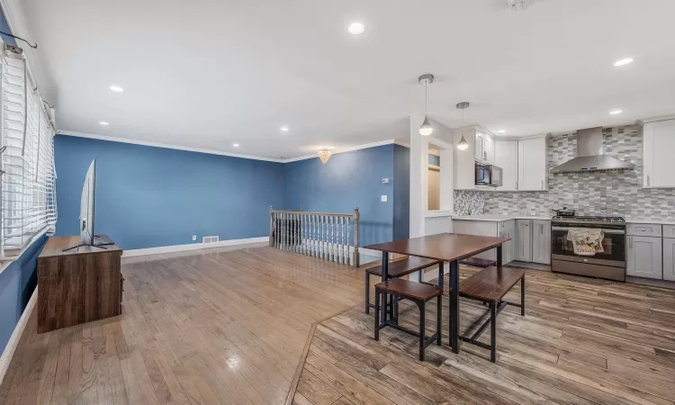 Dining area with visible vents, baseboards, wood finished floors, crown molding, and recessed lighting