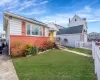 View of front of house with brick siding, a front yard, and fence