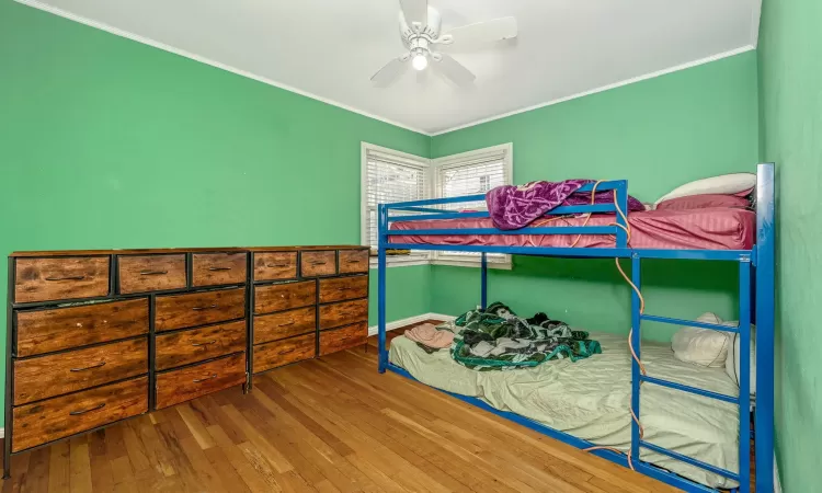 Bedroom with ornamental molding, a ceiling fan, and hardwood / wood-style flooring