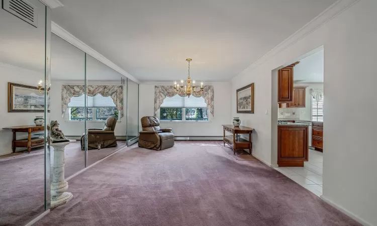 Living area featuring a baseboard heating unit, light colored carpet, a chandelier, and visible vents