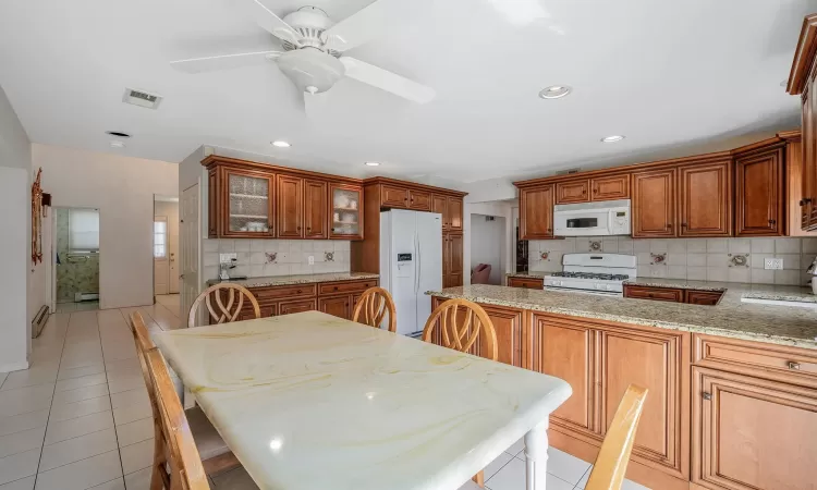 Kitchen featuring brown cabinetry, white appliances, a sink, and a peninsula