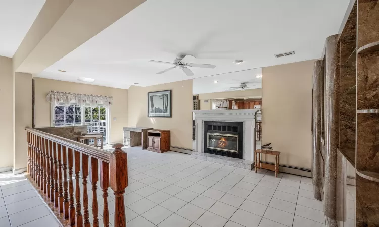 Dining area featuring light tile patterned floors, ceiling fan, a fireplace, and baseboards