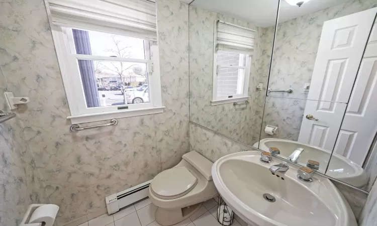 Half bath featuring a sink, baseboard heating, and wallpapered walls