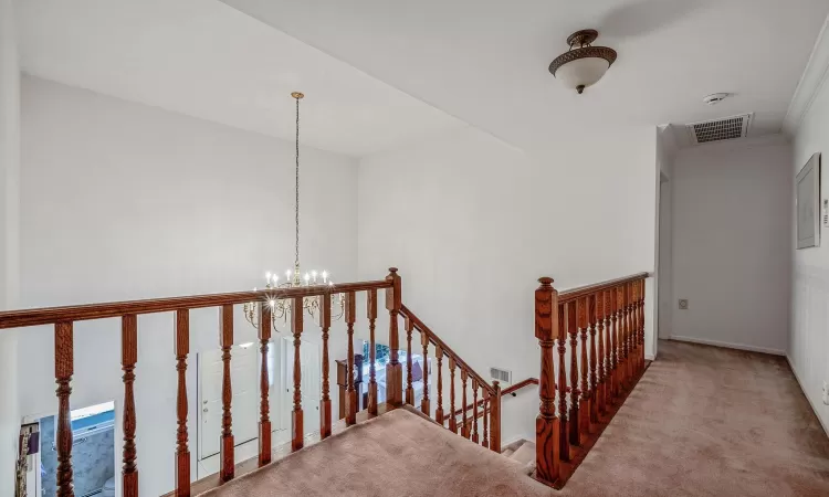 Stairs with carpet floors, visible vents, and a notable chandelier