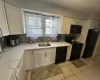 Kitchen featuring tasteful backsplash, white cabinets, a sink, and black appliances