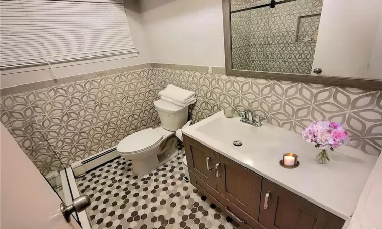 Half bathroom with wainscoting, vanity, toilet, and tile walls