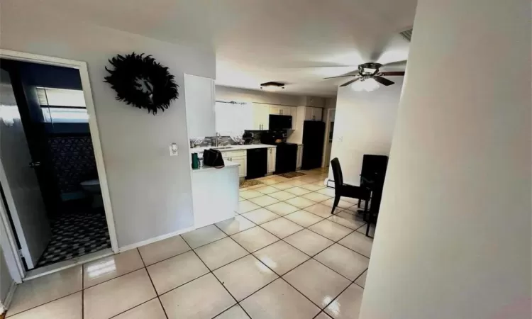 Kitchen featuring light tile patterned floors, light countertops, a ceiling fan, white cabinets, and black appliances