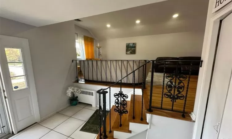 Stairway with recessed lighting, baseboards, vaulted ceiling, tile patterned floors, and radiator