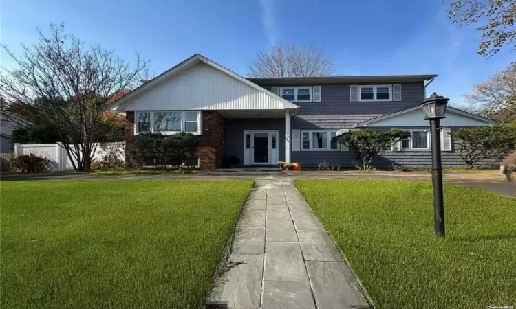 View of front of house with brick siding, fence, and a front yard