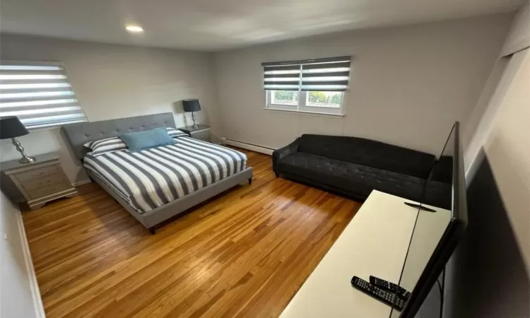 Bedroom with a baseboard radiator, wood finished floors, and recessed lighting