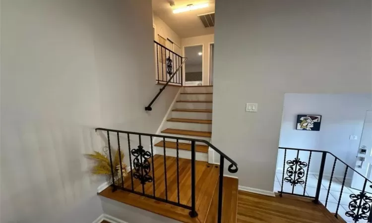 Stairs featuring visible vents, baseboards, and wood finished floors