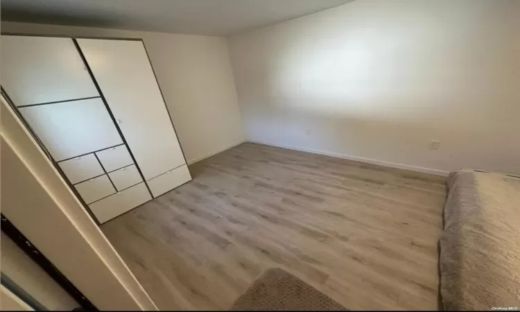 Unfurnished bedroom with light wood-style floors, a closet, and baseboards