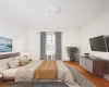 Bedroom featuring radiator, light wood-style flooring, and crown molding