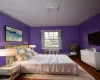 Bedroom featuring radiator heating unit, crown molding, and wood finished floors