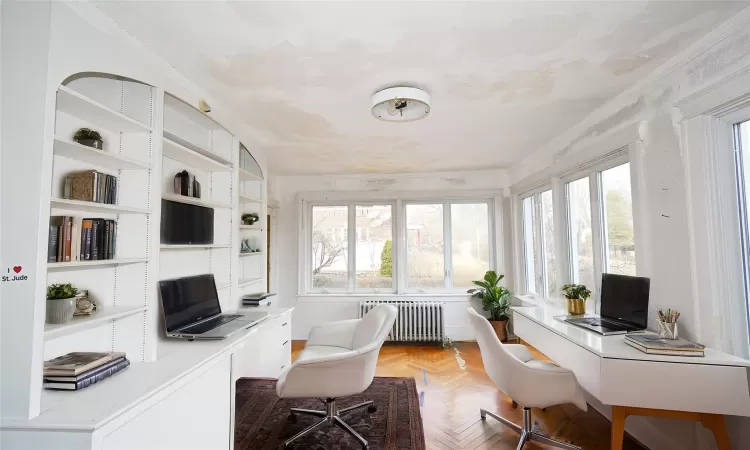 Home office featuring radiator, a healthy amount of sunlight, crown molding, and built in desk