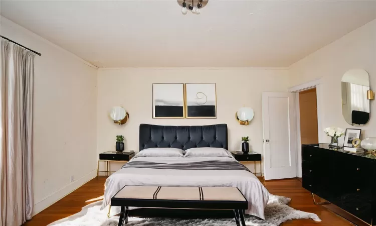 Bedroom featuring ornamental molding, wood finished floors, and baseboards