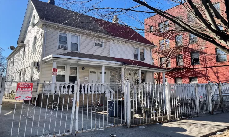 View of front of house featuring a porch, a chimney, a wall mounted air conditioner, and a fenced front yard