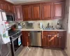 Kitchen featuring light stone counters, a sink, light wood-style floors, appliances with stainless steel finishes, and backsplash